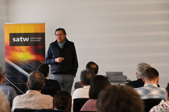 Lecturer in front of audience with SATW banner in the background