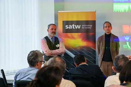 Two men present in front of a satw banner