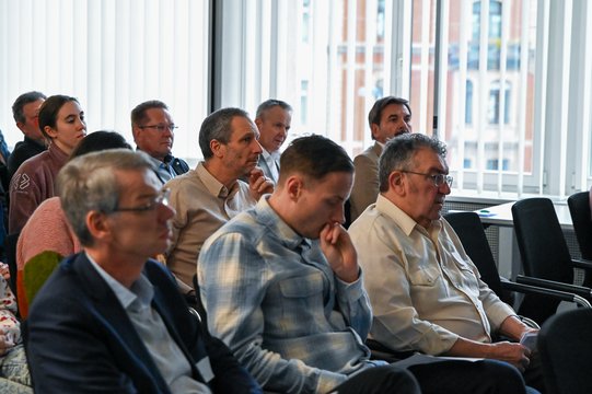 People sit in a conference room and listen attentively.